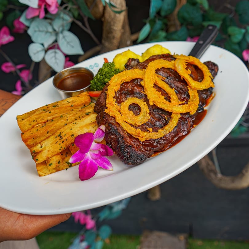 Grilled steak topped with onion rings, served with yuca fries, broccoli, and a dipping sauce.